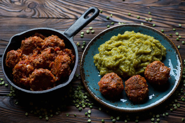 Roasted meatballs with boiled peas on a rustic wooden surface