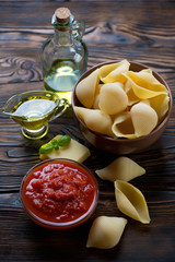 Uncooked conchiglioni with various italian ingredients, close-up