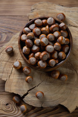 Bowl full of hazelnuts over wooden background, studio shot