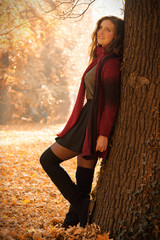 Hübsch junge Frau im Herbstwald lehnt an einem Baum