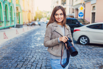 Happy woman on vacation photographing with camera on the city street