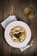 Italian pasta with chicken, cream sauce and basil over grunge wooden table. Delicious dinner concept. Top view. Space for text