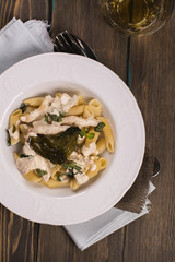 Italian pasta with chicken, cream sauce and basil over grunge wooden table. Delicious dinner concept. Top view. Space for text