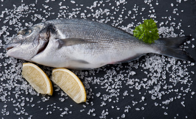 fresh raw dorado fish with spices and herbs on black background, top view