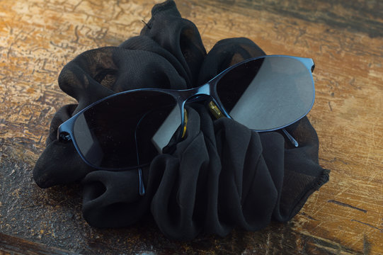 Occhiali da sole su sfondo scuro, sfondo nero, occhiali da sole alla moda su tavolo, con fiocco nero