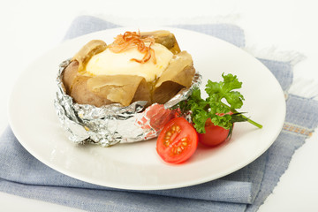 Baked potato with cheese in foliage with fresh tomato