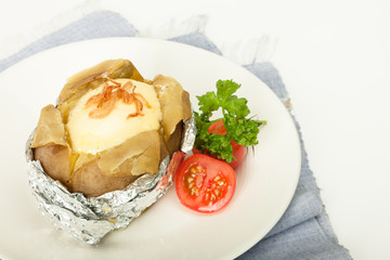 Baked potato with cheese in foliage with fresh tomato
