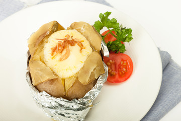 Baked potato with cheese in foliage with fresh tomato