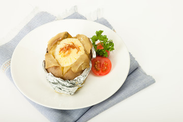 Baked potato with cheese in foliage with fresh tomato