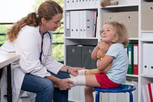 female doctor bandaging the leg from a of girl
