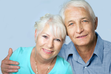  Seniorenpaar Porträt, Mann hält seine Frau im Arm, beide lächeln in die Kamera