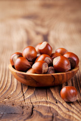 Hazelnuts in a wooden bowl. Wooden background. 