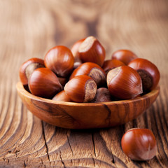 Hazelnuts in a wooden bowl. Wooden background. 