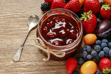 Jar of strawberry jam and raw fruits