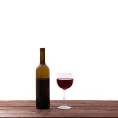 Glass and bottle of red wine on wooden table isolated.