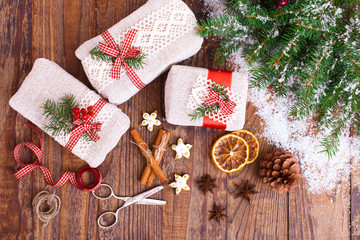 Handmade gift boxes near Christmas tree with cookies and spices.