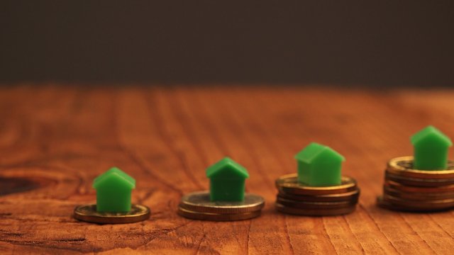 Home mortgage concept with small plastic house models on top of stacked coins