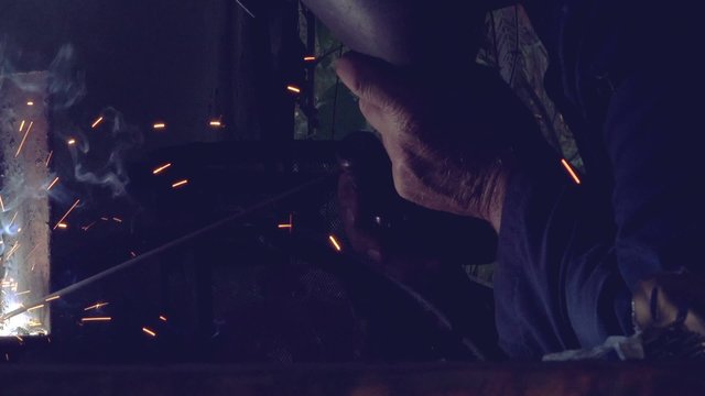 Slider shot of worker arc welding in workshop