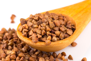 Uncooked buckwheat on wooden spoon