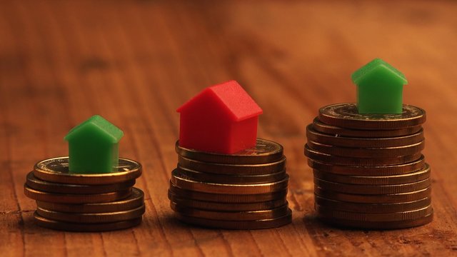 House mortgage concept with small plastic house models on top of stacked coins