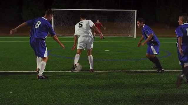A soccer player dribbles down the field and makes a goal and the team celebrates
