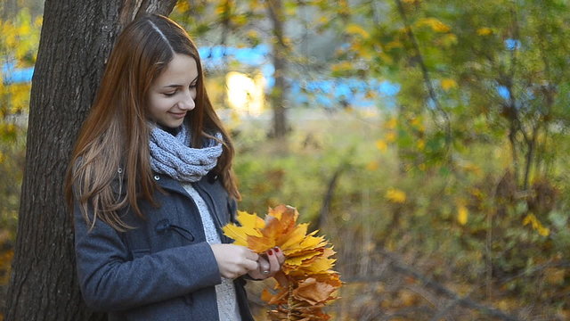 Cute girl makes a circlet of leaves. Beautiful young woman makes a wreath.