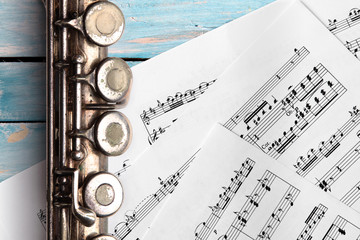 Old flute with sheet music on blue wooden boards