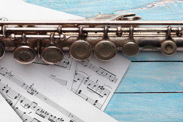Obraz premium Old flute with sheet music on blue wooden boards