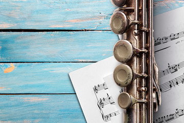 Obraz premium Old flute with sheet music on blue wooden boards
