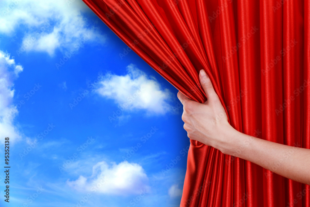 Wall mural human hand opens red curtain on sky background