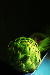 Artichokes on color wooden table, on dark background