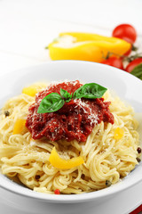 Spaghetti with tomato sauce and cheese on white plate, on color wooden background