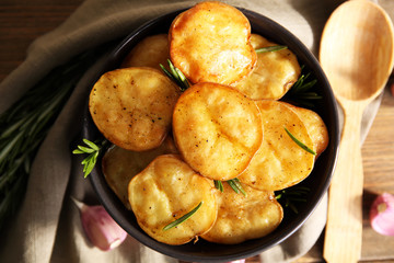Delicious baked potato with rosemary in bowl on table close up