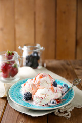 Delicious ice cream with fresh frozen berries and sauce, on wooden background