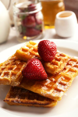 Sweet homemade waffles with strawberries  on plate, on table background