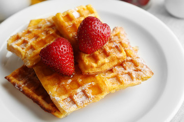 Sweet homemade waffles with strawberries  on plate, on table background