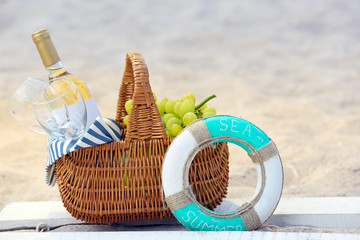 Fototapeta premium Picnic basket with bottle of wine on sand beach