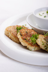 .Cabbage pancakes with parsley and yogurt dressing on a white plate.