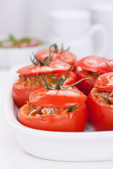 Stuffed tomatoes with tuna, parmesan and green beans in a white ceramic pan.
