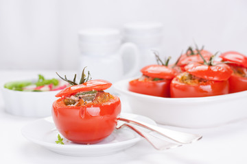 Stuffed tomatoes with tuna, parmesan and green beans in a white ceramic pan.
