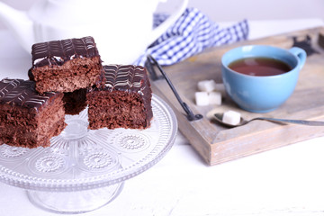 Served table with a cup of tea and chocolate cakes close-up