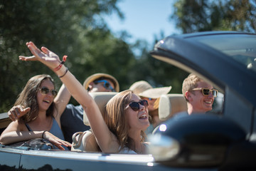 young people having fun in a black convertible by a sunny day