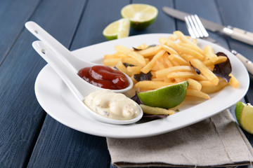 French fried potatoes with sauce and lime on white tray