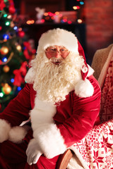 Santa Claus sitting in comfortable chair near fireplace at home