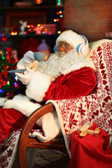 Obraz premium Santa Claus sitting with headphones sitting in comfortable rocking chair at home