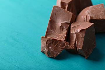 Milk chocolate pieces on color wooden background