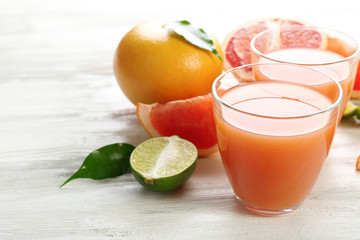 Naklejka na ściany i meble Two glasses of citrus juice and fresh fruits on light wooden background