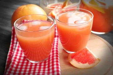 Citrus juice with ice and fresh fruits on cutting board