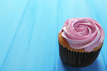 Tasty cupcake on color wooden background