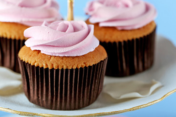 Tasty cupcakes on stand, on color background